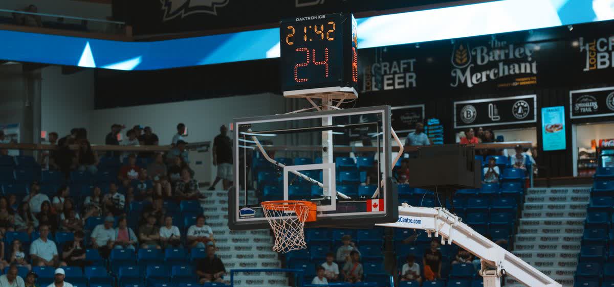 A basketball hoop and shot clock in an arena with spectators