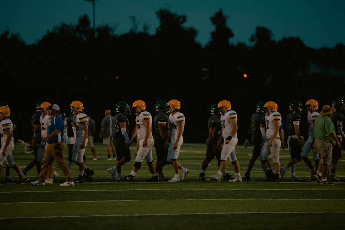 Football players on a field under the lights at night