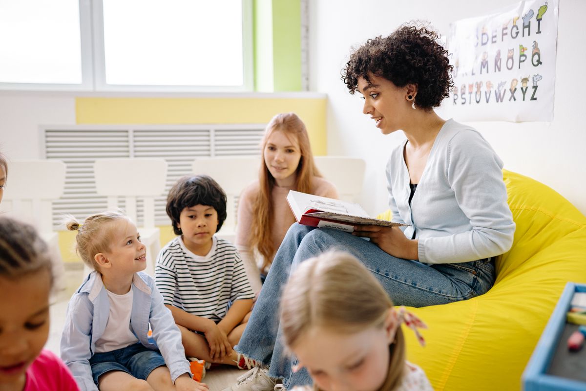 A storyteller reading a picture book to a circle of children